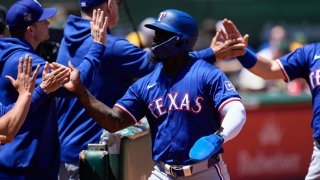 Texas Rangers’ Adolis García, center, celebrates with teammates at the dugout after scoring against the Oakland Athletics on Jonah Heim’s single during the second inning of a baseball game Tuesday, May 7, 2024, in Oakland, Calif.