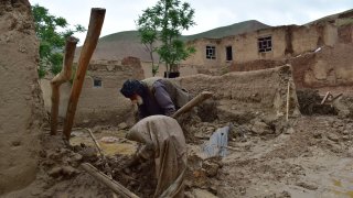 An elderly man collects his belongings from his damaged home after heavy flooding