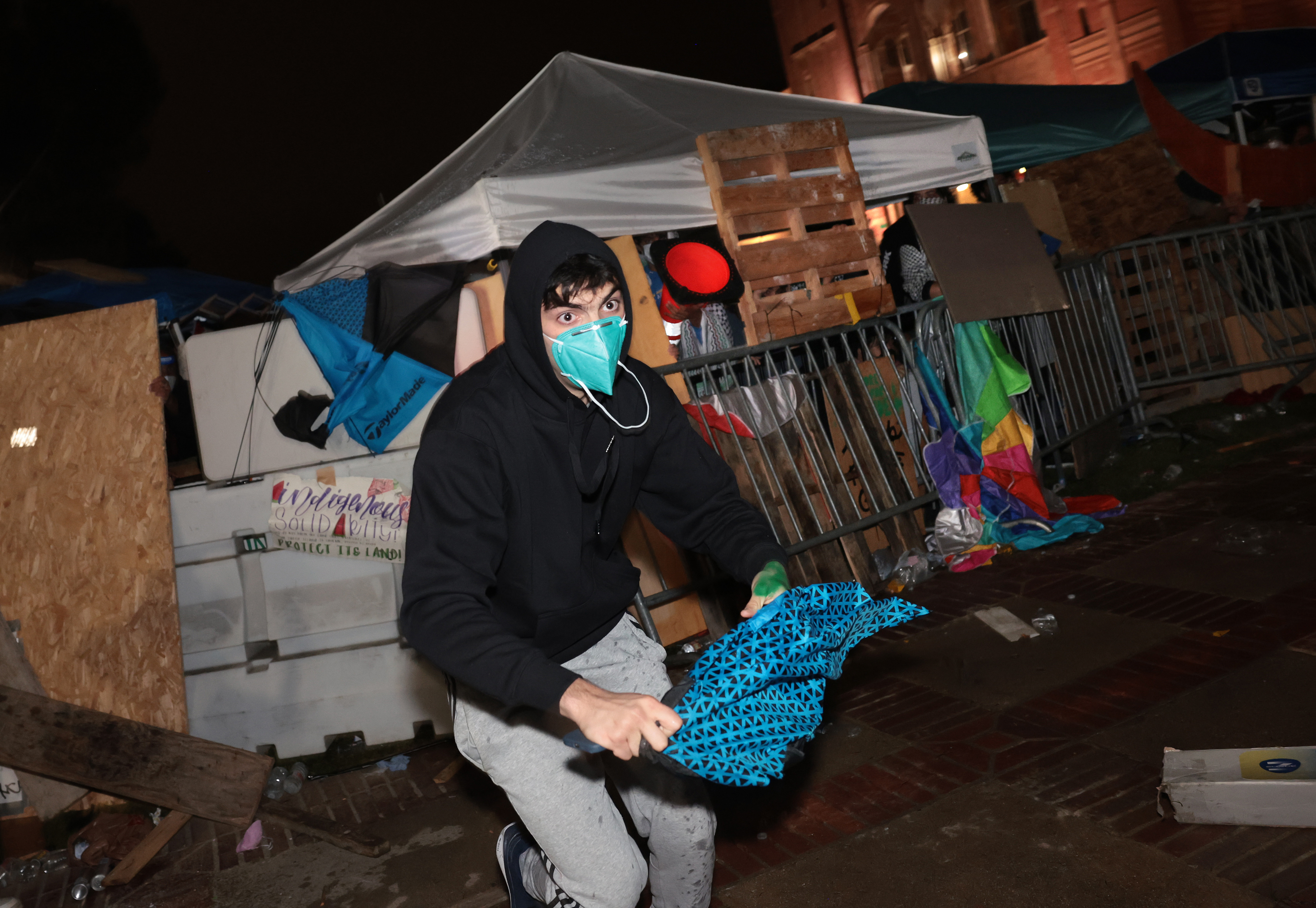 LOS ANGELES, CALIFORNIA – May 1: A pro-Israeli supporter takes an umbrella from a Pro-Palestinian encampment from at UCLA early Wednesday morning. (Wally Skalij/Los Angeles Times via Getty Images)