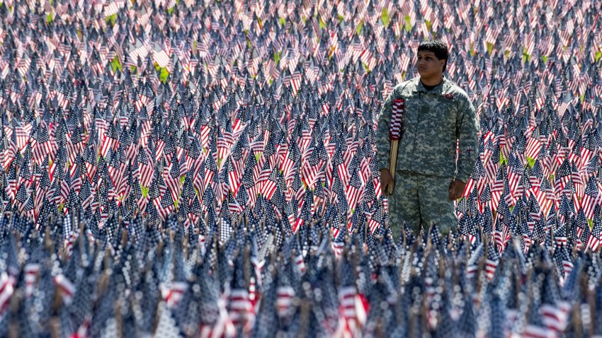 Eric Teo Lopez, 16, of the Fitchburg ROTC program works to replace damaged US flags as he stands in a field of some 37,000 US flags as part of a Memorial Day Flag Garden by the Soldiers and Sailors Monument in Boston Common on May 25, 2024.