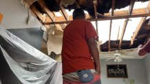 Max Perez looks up at the whole in his ceiling, after winds tore the roof off his buildings Thursday evening. (NBC 5/Tahera Rahman)