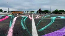 Artist painting Meow Wolf Grapevine parking lot mural