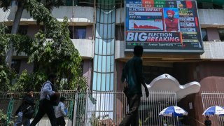 Pedestrians walk past a digital broadcast displaying share prices on the facade of Bombay Stock Exchange (BSE) on the day of India’s general election result in Mumbai on June 4, 2024.