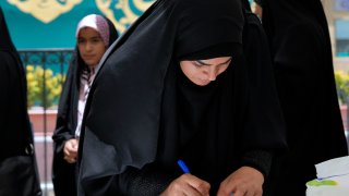 A woman fills out her ballot during the Iranian presidential election in a polling station at the shrine of Saint Saleh in northern Tehran, Iran, Friday, June 28, 2024.