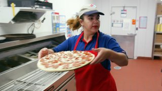 A Domino’s employee preparing a pizza.