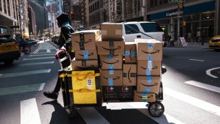 An Amazon contract worker pulls a cart of packages for delivery in New York, US, on Monday, April 22, 2024. 