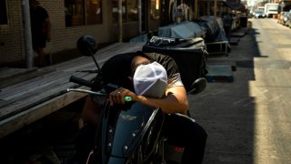 A delivery driver takes a break in the shade during high temperatures in Philadelphia on June 21, 2024.