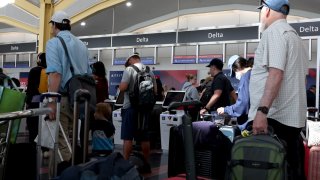 Travelers wait in line at a Delta Airlines counter at Ronald Reagan National Airport in Arlington, Virginia, on July 19, 2024. Airlines around the world experienced disruption on an unprecedented scale after a widespread global computer outage grounded planes and created chaos at airports.