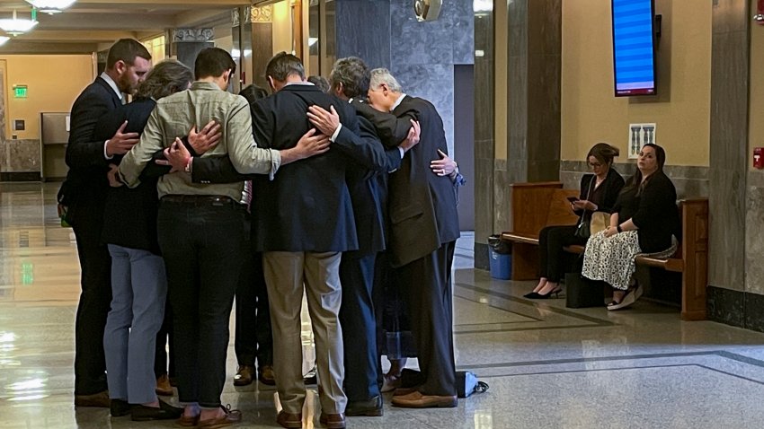 Covenant School parents and their attorneys huddle in prayer outside a courtroom