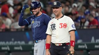 Texas Rangers first baseman Nathaniel Lowe (30) and his brother Tampa Bay Rays’ Josh Lowe, left, laugh at first base after Josh singled during the sixth inning of a baseball game in Arlington, Texas, Friday, July 5, 2024. (AP Photo/LM Otero)