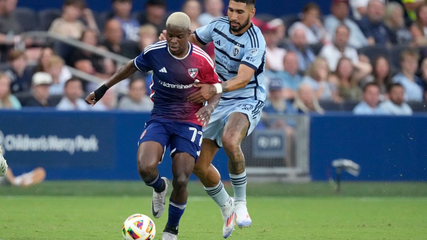 FC Dallas midfielder Bernard Kamungo (77) is chased by Sporting Kansas City defender Robert Castellanos (19) during the first half of an MLS soccer match Sunday, July 7, 2024, in Kansas City, Kan. (AP Photo/Charlie Riedel)