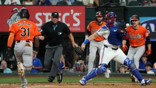 The ball gets away from Texas Rangers catcher Andrew Knizner as Baltimore Orioles’ Cedric Mullins (31) scores on a on a single by Ramon Urias as Gunnar Henderson (2) and Colton Cowser, who also scored on the play, look on during the second inning of a baseball game Saturday, July 20, 2024, in Arlington, Texas. (AP Photo/Jeffrey McWhorter)