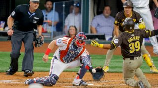 Texas Rangers catcher Andrew Knizner, bottom center, receives a throw from left fielder Wyatt Langford and tags San Diego Padres’ Donovan Solano (39) out at home plate during the fourth inning of a baseball game Thursday, July 4, 2024, in Arlington, Texas. (AP Photo/Gareth Patterson)