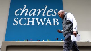 Pedestrians walk by a sign posted outside of a Charles Schwab office in San Francisco on April 17, 2023.