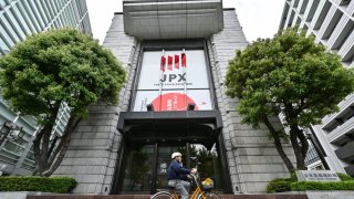 A cycler passes the entrance to the Tokyo Stock Exchange (TSE) headquarters building in the Nihonbashi area of Tokyo on May 2, 2024.