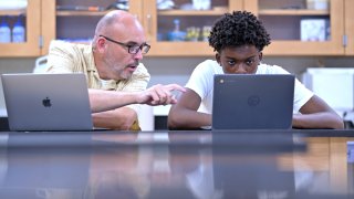 History teacher Matt Brophy, left, works with Flerentin “Flex” Jean-Baptiste, 16, of Medford, Mass., on making up late assignments during summer school at Medford High School, Friday, Aug. 2, 2024, in Medford.