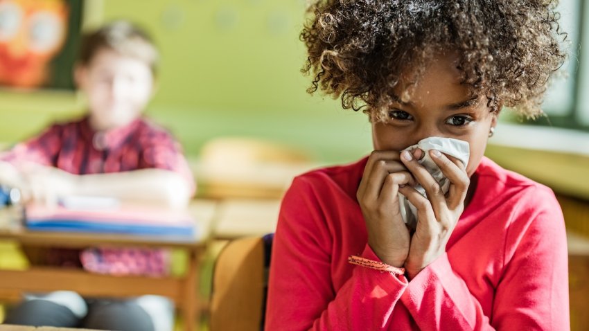 Ill black schoolgirl blowing her nose during a class at elementary school.