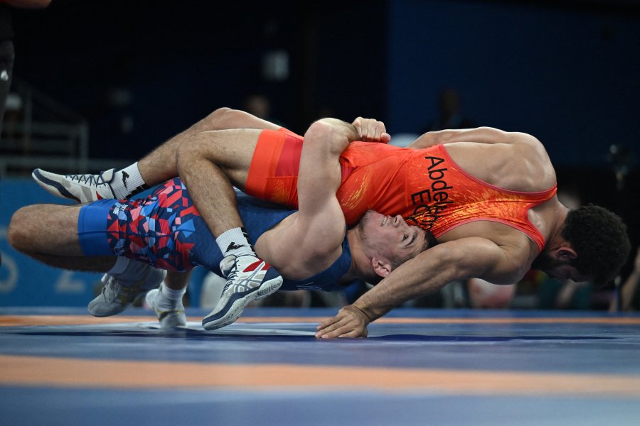 Egypt's Mahmoud Abdelrahman wrestles Uzbekistan's Aram Vardanyan (blue) in their men's greco-roman 77kg wrestling early rounds match at the Champ-de-Mars Arena during the Paris 2024 Olympic Games, in Paris on August 6, 2024