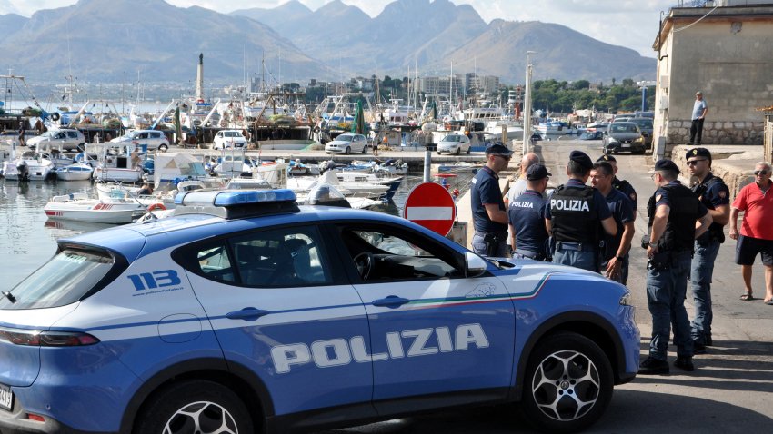 Italian police officers stand at the port as the search continues for six passengers missing from a sailboat that sank off the coast of Porticello, north-western Sicily, on 19 August 2024.