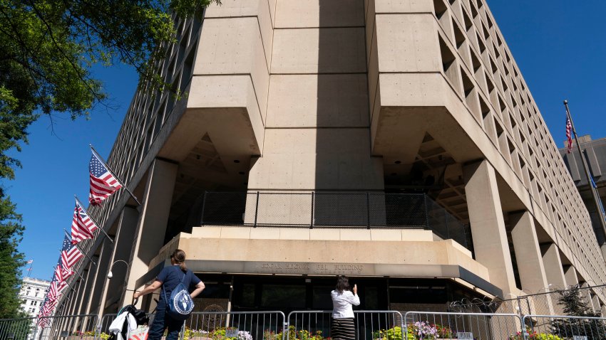 FILE – People take photos of the FBI building headquarters in Washington, Aug. 13, 2022. A federal judge has held veteran investigative reporter Catherine Herridge in civil contempt for refusing to divulge her source for a series of Fox News stories about a Chinese American scientist who was investigated by the FBI but never charged.