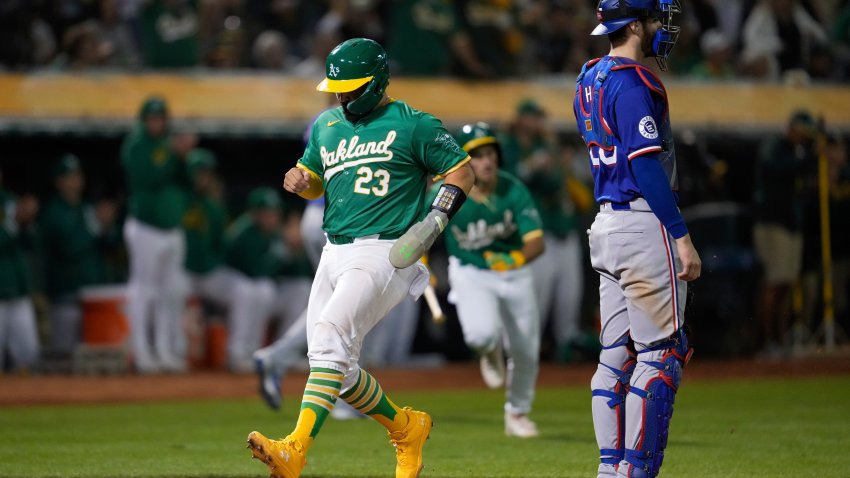 Oakland Athletics’ Shea Langeliers (23) scores next to Texas Rangers catcher Jonah Heim on Zack Gelof’s sacrifice fly during the sixth inning of a baseball game Tuesday, Sept. 24, 2024, in Oakland, Calif. (AP Photo/Godofredo A. Vásquez)