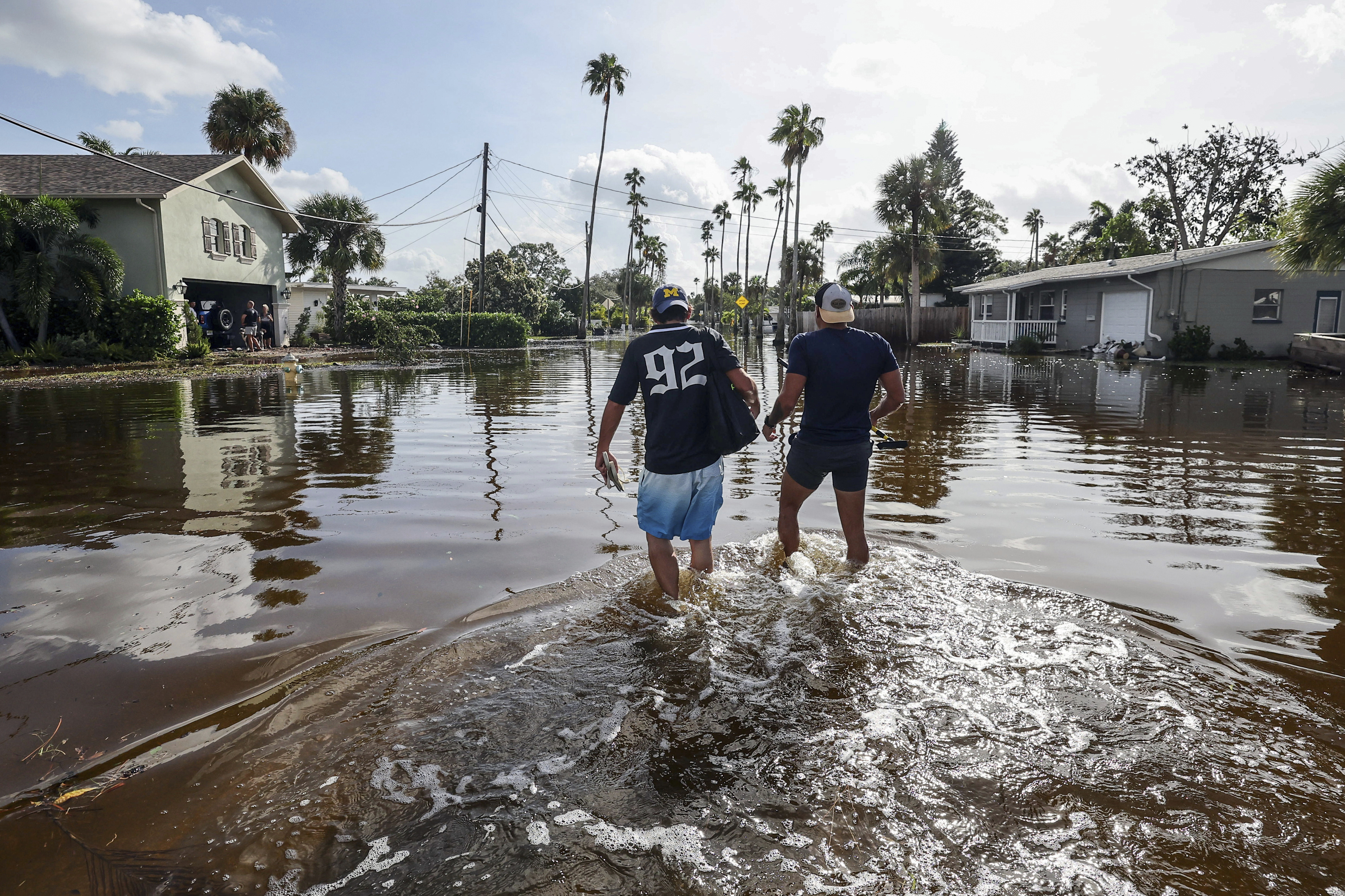 Thomas Chaves, left, and Vinny Almeida walk through floodwaters from Hurricane Helene in an attempt to reach Chaves’s mother’s house in the Shore Acres neighborhood Friday, Sept. 27, 2024, in St. Petersburg, Fla.