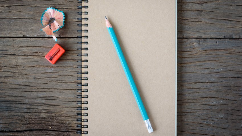 File. An opened notebook with pencil,orange and Pencil Sharpener on old wooden table.