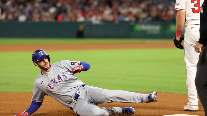 Sep 28, 2024; Anaheim, California, USA;  Texas Rangers pinch hitter Jonah Heim (28) slides to a third on a triple during the eighth inning against the Los Angeles Angels at Angel Stadium. Mandatory Credit: Kiyoshi Mio-Imagn Images