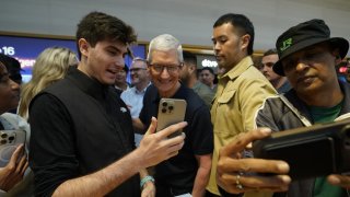 Apple CEO Tim Cook (C) joins customers during Apple’s iPhone 16 launch in New York on September 20, 2024. 