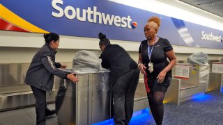 Southwest Airlines employees cover the ticket counters with plastic wrap just before Tampa International Airport was closing due to the possible arrival of Hurricane Milton Tuesday, Oct. 8, 2024, in Tampa, Fla.