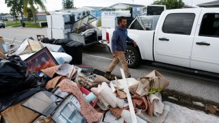 A contractor walks by debris left by Hurricane Helene along the roadside, as residents prepare to evacuate ahead of the arrival of Hurricane Milton in New Port Richey, Florida., U.S., October 8, 2024.