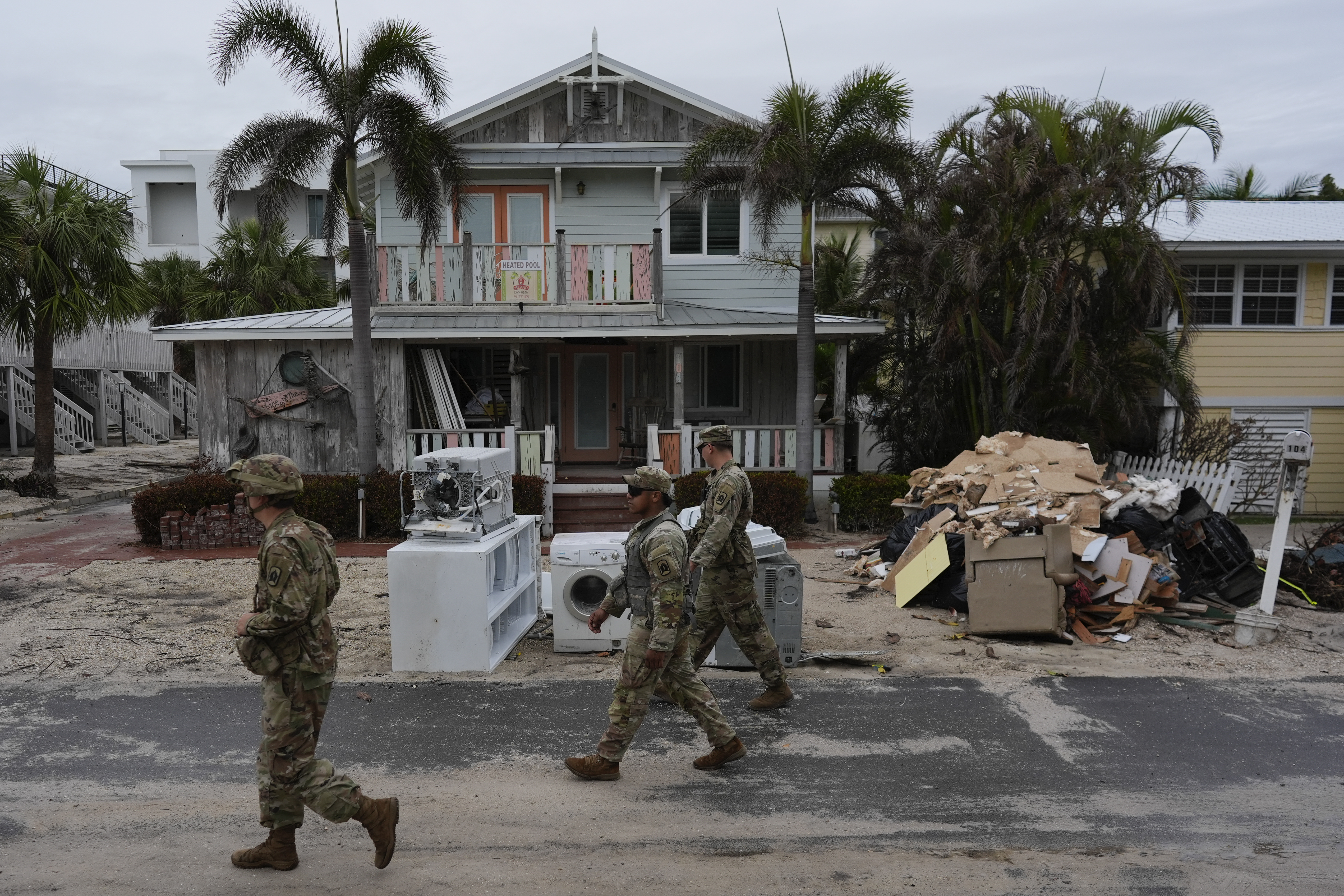 Members of the Florida Army National Guard check for any remaining residents in nearly-deserted Bradenton Beach, where piles of debris from Hurricane Helene flooding still sits outside damaged homes ahead of the arrival of Hurricane Milton, Tuesday, Oct. 8, 2024, on Anna Maria Island, Florida.