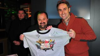 (L-R) Frank Fritz and Mike Wolfe from American Pickers autograph a t-shirt for a fan during the grand opening of the History Pop Shop at History Pop Shop on December 6, 2010 in New York City. (Photo by Brian Killian/WireImage)