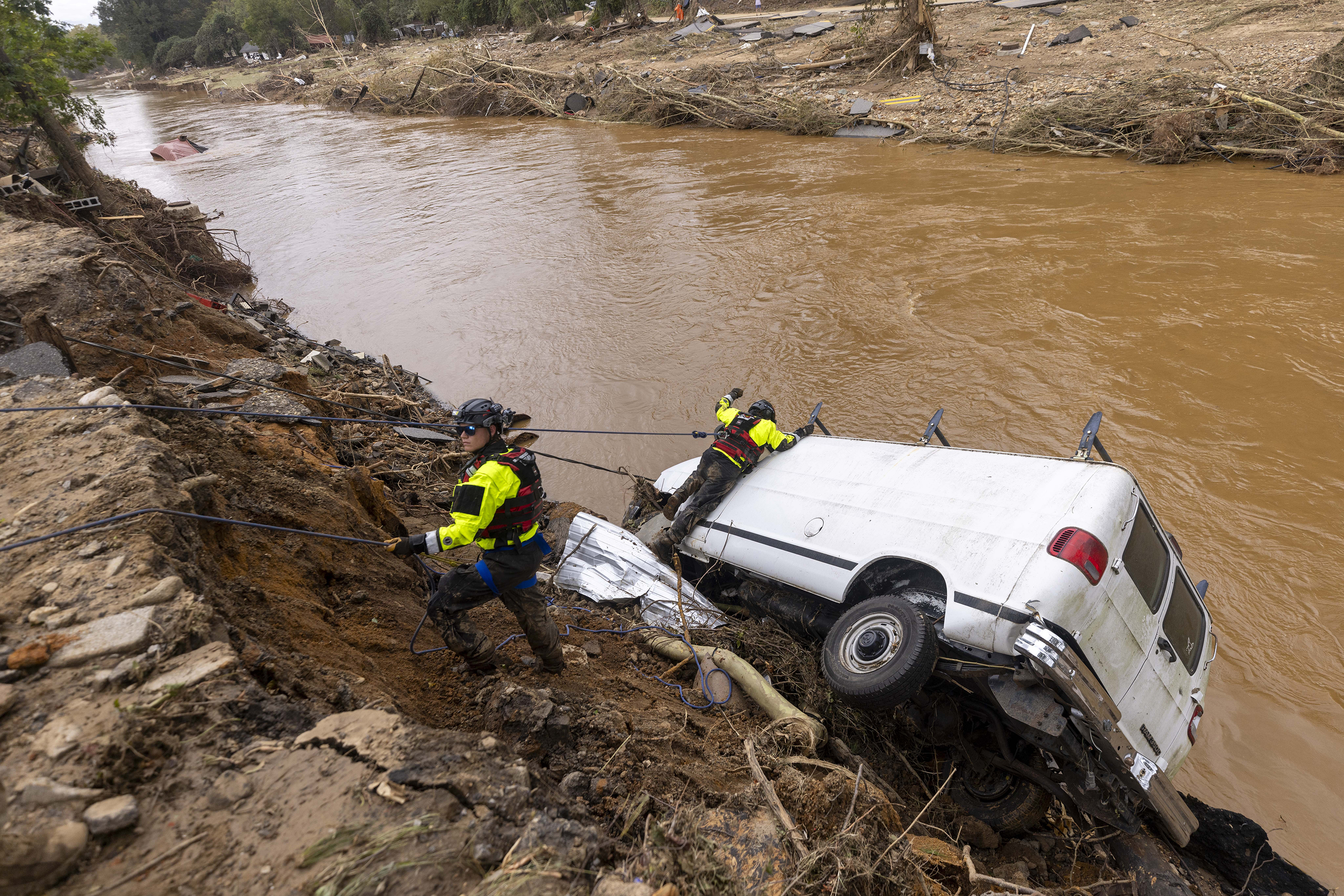 A search and rescue team out of Atlantic Beach, N.C. examines a van swept into the river in Swannanoa, N.C. by flooding from Helene.