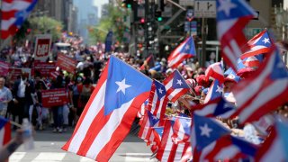 Parade attendees wave Puerto Rican flags on Fifth Avenue in Manhattan during the annual Puerto Rico Day Parade. 