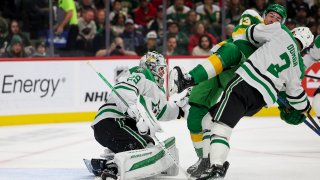 Dallas Stars goaltender Jake Oettinger (29) saves the puck while Minnesota Wild center Yakov Trenin (13) collides with Stars defenseman Mathew Dumba (3) during the first period of an NHL hockey game, Saturday, Nov. 16, 2024, in St. Paul, Minn. (AP Photo/Ellen Schmidt)