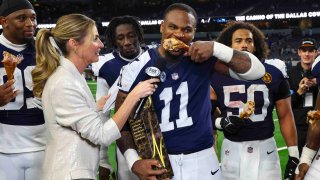 Dallas Cowboys linebacker Micah Parsons (11) eats a turkey leg as received gar John Madden Trophy from Erin Andrews following an NFL football game against the New York Giants in Arlington, Texas, Thursday, Nov. 28, 2024.