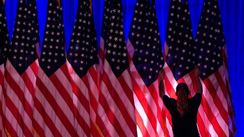 A worker adjusts the flags on stage ahead of an election night watch party for Republican presidential nominee former President Donald Trump, Nov. 5, 2024, in West Palm Beach, Fla.