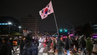 A man holds the South Korea flag outside the National Assembly in Seoul on December 4, 2024, after President Yoon Suk Yeol declared emergency martial law. South Korea’s President Yoon Suk Yeol on December 3 declared emergency martial law, saying the step was necessary to protect the country from “communist forces” amid parliamentary wrangling over a budget bill. 