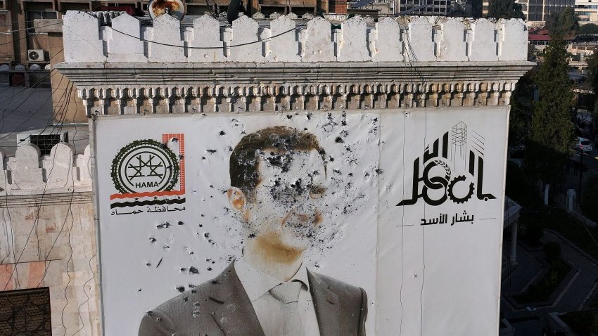 TOPSHOT – This aerial picture shows a bullet-riddled portrait of Syrian President Bashar al-Assad adorning Hama’s municipality building after it was defaced following the capture of the city by anti government fighters, on December 6, 2024. 