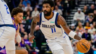 Dallas Mavericks guard Kyrie Irving (11) dribbles past defender Utah Jazz guard Keyonte George (center) during the first half of an NBA basketball game Saturday, Nov. 30, 2024, in Salt Lake City. (AP Photo/Tyler Tate)