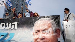 Supporters of Israel’s Prime Minster Benjamin Netanyahu, seen in poster, gather outside a court in Tel Aviv, Israel, Tuesday, Dec. 10, 2024 as Netanyahu is set to take the stand in his long-running trial on corruption charges.