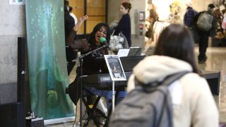 Roz McCommon performs amid travelers at Seattle-Tacoma International Airport on November 26, 2024, in SeaTac, Wash.