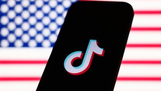 TikTok logo displayed on a phone with an American flag in the background