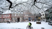 A man rides bicycle on a snow-covered street after snowfall in Frankfurt am Main, western Germany, on December 29, 2024. 