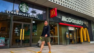 A pedestrian walks past Starbucks and McDonald’s outlets located side by side in a modern commercial building on November 30, 2024, in Shenzhen, Guangdong Province, China. 