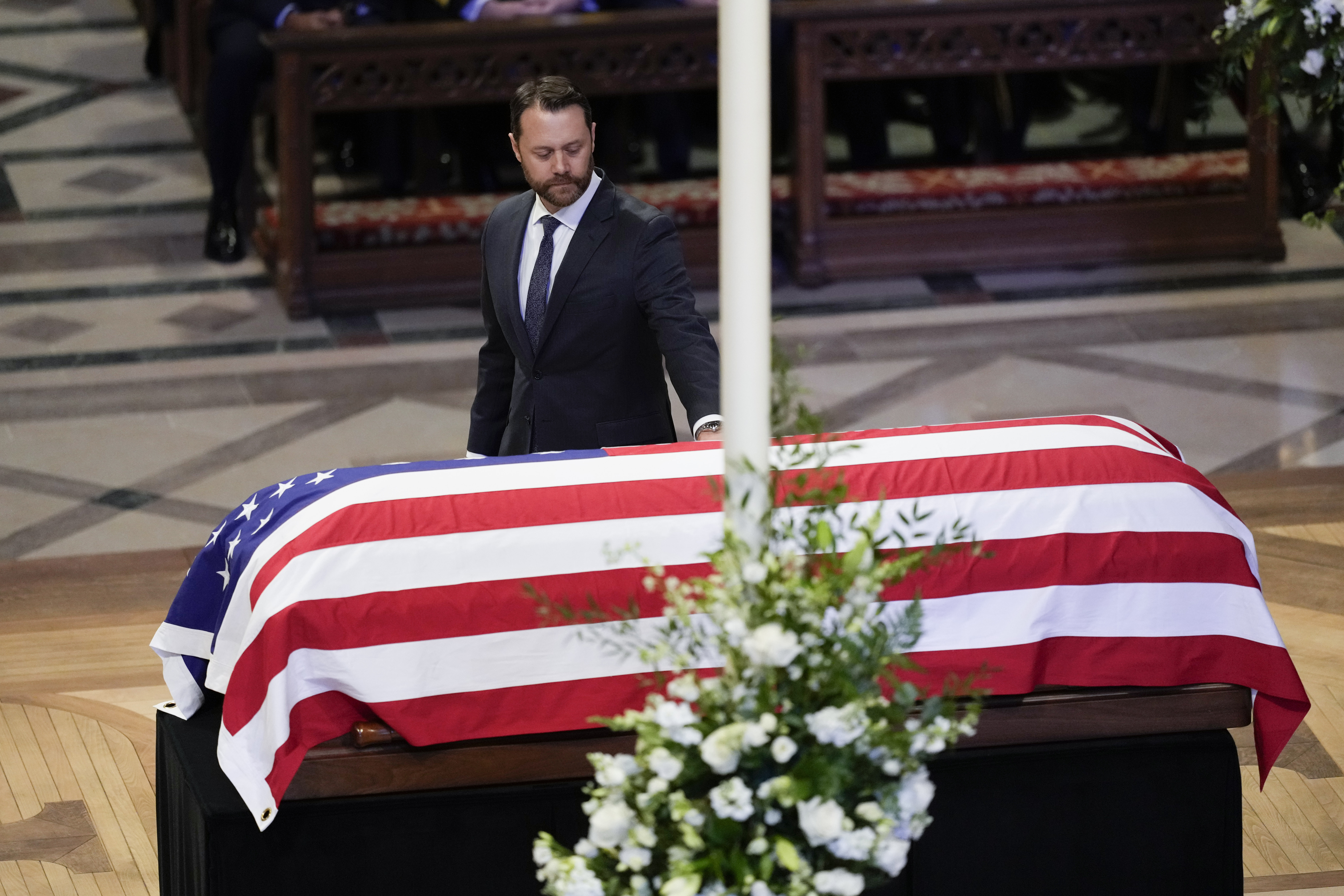 Grandson Jason Carter, walks by and touches the flag-draped casket of former President Jimmy Carter, after speaking a tribute at the state funeral for Carter at Washington National Cathedral, Thursday, Jan. 9, 2025, in Washington.