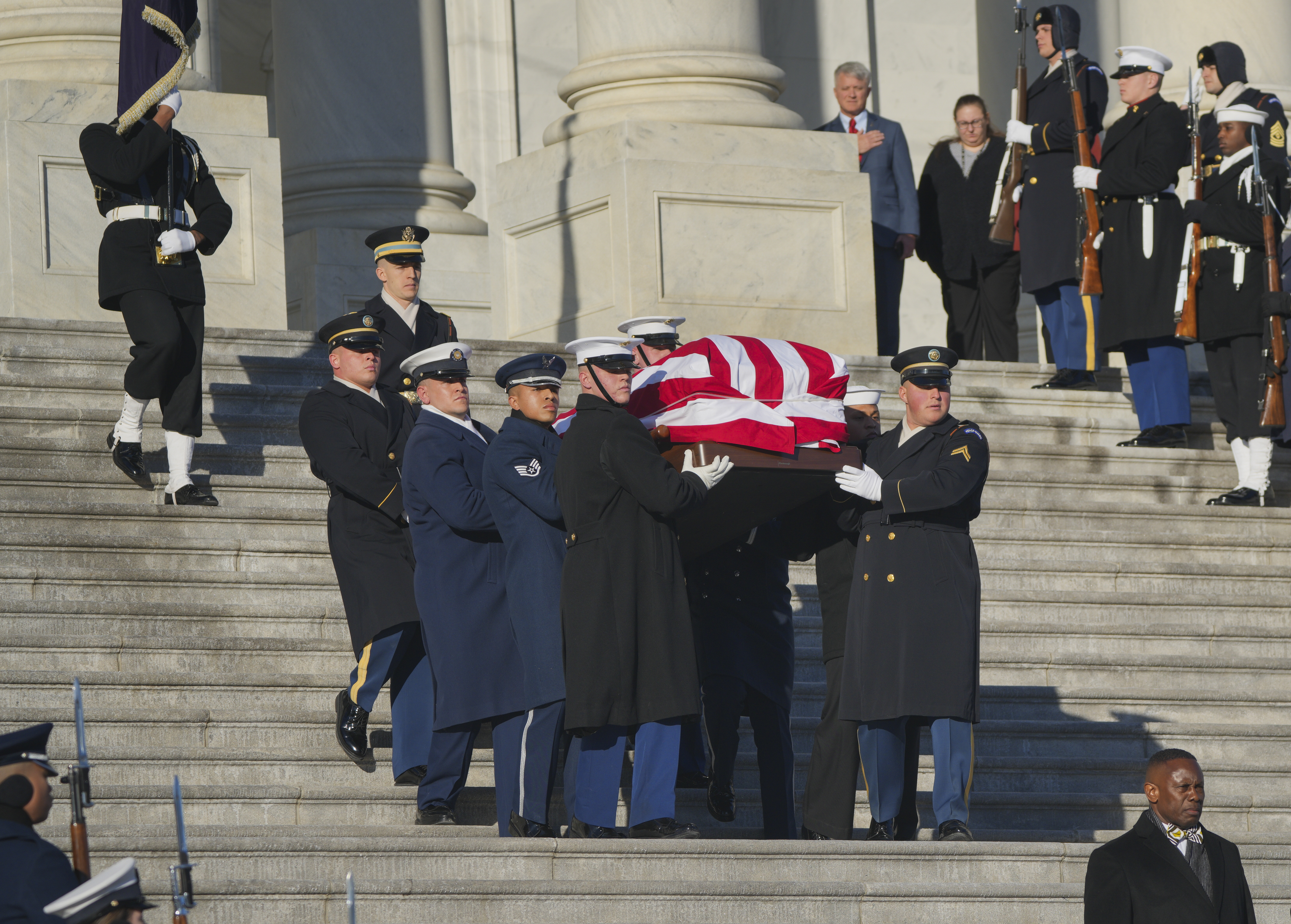 The flag-draped casket of former U.S. President Jimmy Carter is carried by a joint services military honor guard down the steps of the U.S. Capitol.