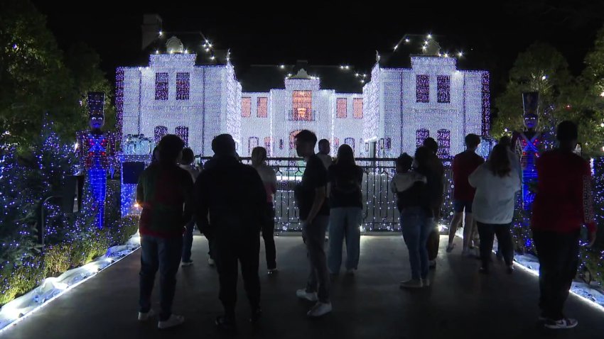 People stand in the driveway of the home on Deloache Avenue in Preston Hollow looking at the holiday lighting display that went viral on social media.