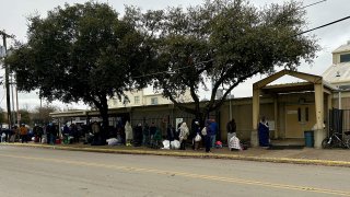 People line up outside a shelter on Hickory Street in Dallas, Feb. 12, 2025.